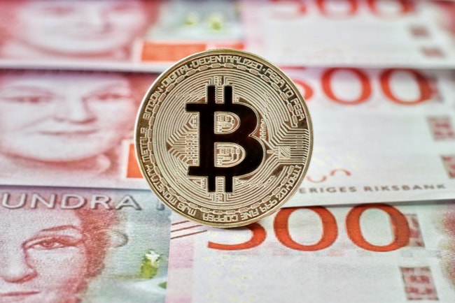 En Bitcoin med svenska sedlar i bakgrunden