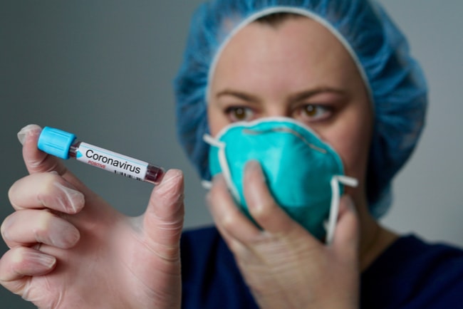 Sjuksköterska håller i ett provrör som innehåller blod och är märkt med texten coronavirus