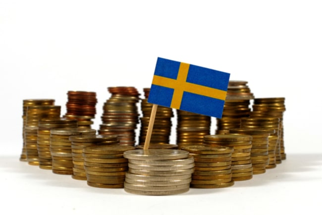 Staplar av mynt i olika storlekar som står i en triangel och med svensk flagga på den främre stapeln.