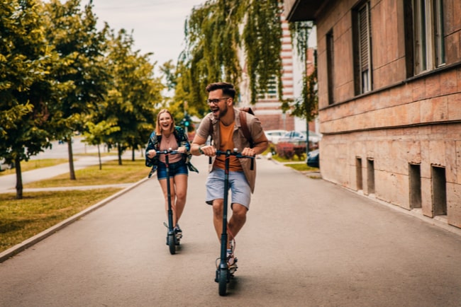 Ung man och kvinna åker på elsparkcyklar under sommaren.