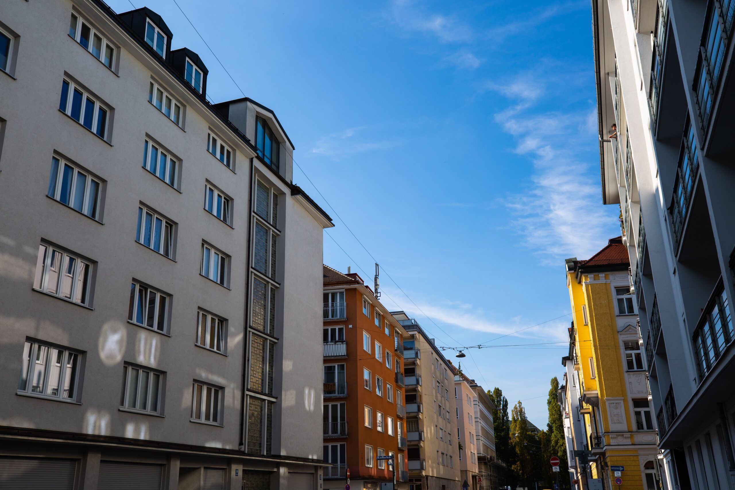 Lägenhetsbyggnader på bägge sidor om en gata samt blå himmel.
